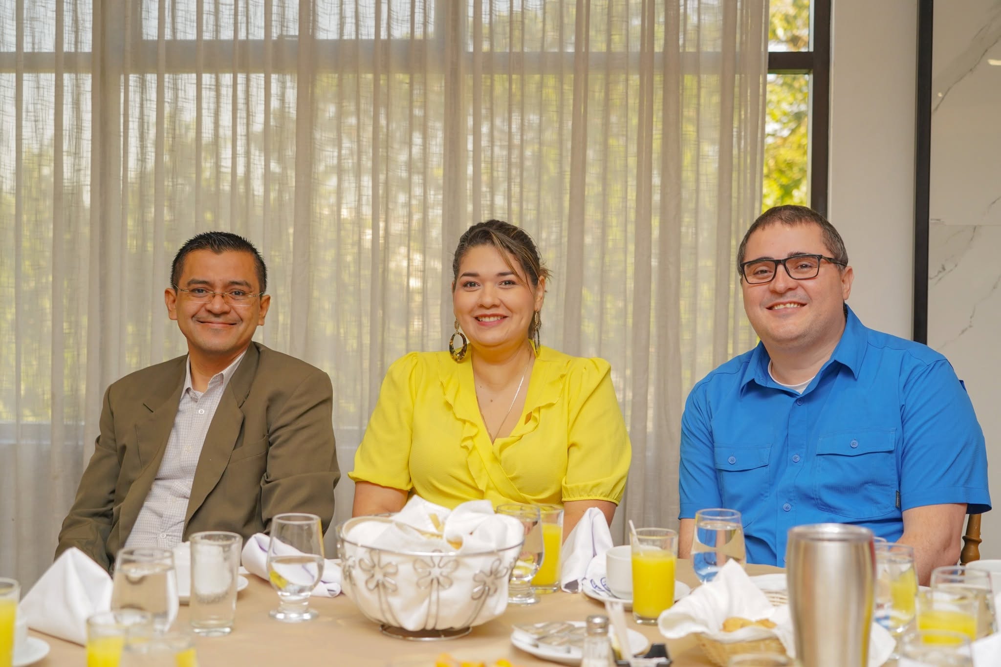 Colaboradores sonriendo en una mesa durante un evento institucional